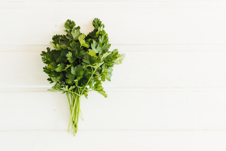 Fresh parsley on wooden background. Organic italian parsley closeup on rustic board, vegetarian food overhead. Bunch of raw cilantro herb flat lay, flat lay, place for design and text.の写真素材