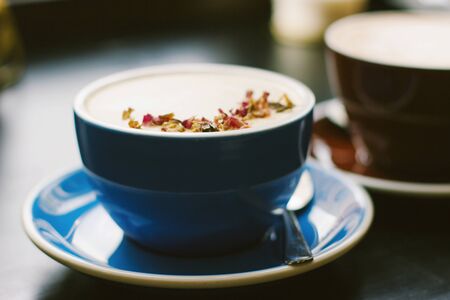 Cups of cappuccino with latte art on black background. Beautiful foam, blue and brown ceramic cups, stylish toning, place for design and text.の写真素材
