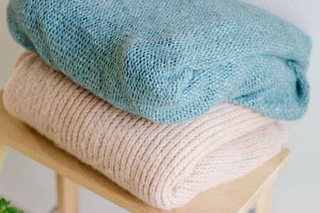 Several warm sweaters on a wooden shelf on a light background. Autumn and winter clothes. A stack of two warm sweaters.の写真素材