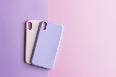 Two silicone cases on purple and pink backgrounds. Pastel pink and purple silicone smartphone cases. Protection for the back cover of the mobile phone with a slot for the camera.の写真素材