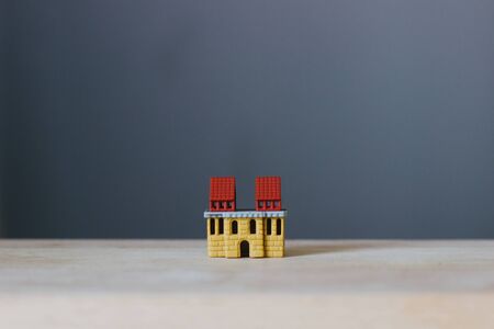 Model house on a wooden surface. A miniature house with a red roof on a wooden layout on a blurred...
