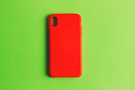 Red smartphone case on a green background. Protective silicone cover for smartphone.の写真素材