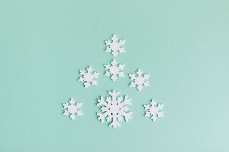 White wooden snowflakes on a light background. Snowflakes are laid out on a mint-colored background in the shape of a Christmas tree.の写真素材