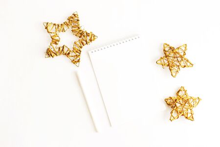 Notebook and a gold star on a white background. A notebook to write down the goals for 2020. Notepad, pen and three gold stars. Selective focus.の写真素材