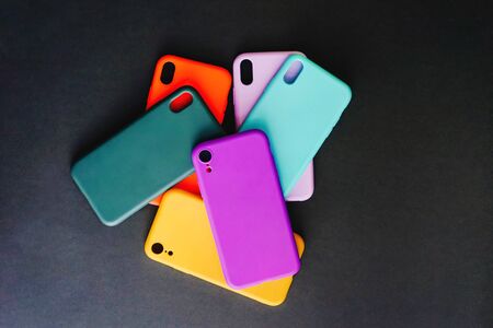 Yellow, red, purple, lilac, green, mint cases for the smartphone on the black background. Protective silicone cases for smartphone. Set of colored silicone covers for smartphone. Selective focus.の写真素材
