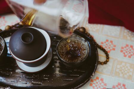 Tea ceremony. The process of spilling the tea on clay cups. Tea master pours Chinese drink. Tea bubble.の写真素材