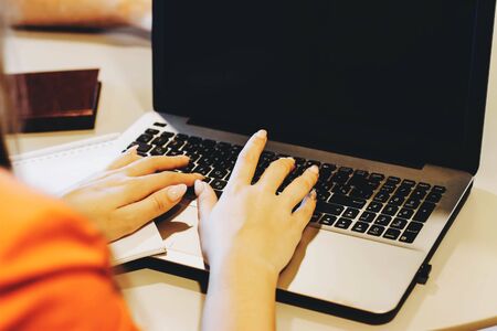 The girl works at the computer. A laptop with a black screen on her lap. The girl works at the computer in a coworking. Marble tiles in the background.の写真素材