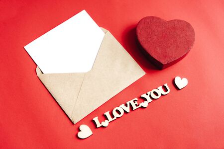 Envelope with a letter, a gift red box in the shape of a heart. Wooden hearts and inscription I love you. Happy Valentine's Day.の写真素材