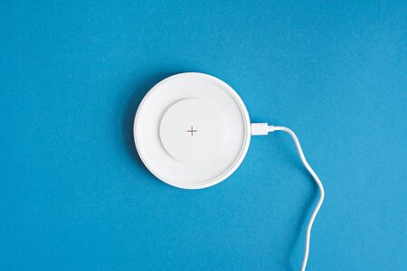 Wireless charging in white lies on a blue background. Fast charge for smartphone.