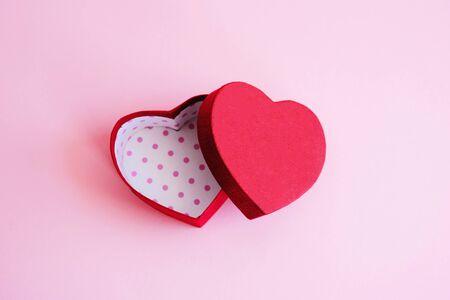 An open red heart-shaped gift box for a loved one. Happy Valentine's Day. Love. The red heart-shaped gift box lies open on a pink background.の写真素材