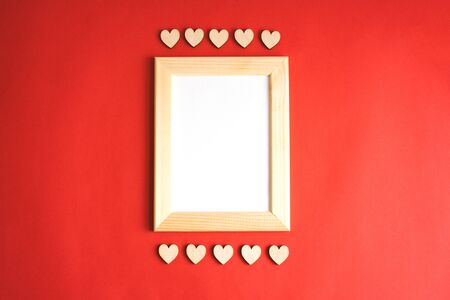 A wooden frame with a white sheet on a red background. Wooden hearts. Happy Valentines Day.の写真素材