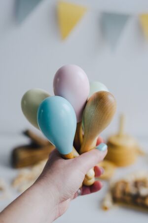 The girl holds in her hand several maracas made of natural wood. Colorful maracas in hand. Children's room. Wooden toys and musical instruments.の写真素材