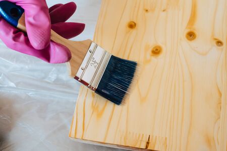 Synthetic brush to apply paint on any surface. Brush with blue bristles. The brush rests on a wooden...
