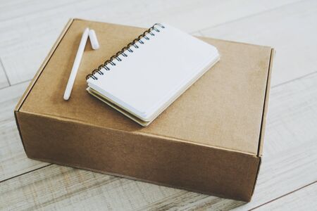 The box delivered by courier to the door. The notebook and the pen are on the box. Shopping online.