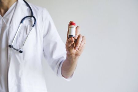 The doctor is holding a tube of medicine in his hand. Vaccine against the virus. Vaccine Covid-19. In the hands of a medical officer, the vaccine against the virus. The doctor is on the front line.の写真素材