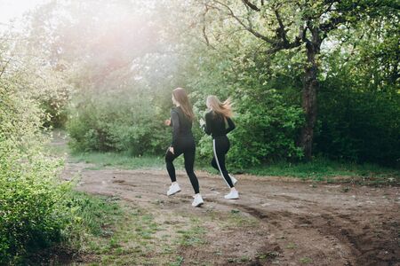 Two girls jogging in the woods. Running with distance.の写真素材