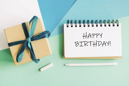 Gift craft box tied with a velvet turquoise ribbon and a notebook. Abstract background. Box and notepad with the inscription Happy birthday.の写真素材