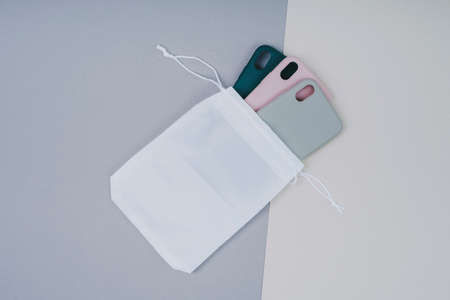A set of smartphone cases in a white eco-bag. Silicone cases on a gray background.の写真素材