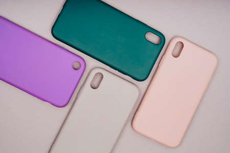A few silicone cases for the smartphone. The phone is in a gray case. Purple, grey, green and pink smartphone cases. Protect your phone.の写真素材