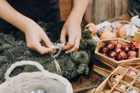 The girl decorates the Christmas wreath with a bow and Christmas toys. Woman making christmas wreath.の写真素材