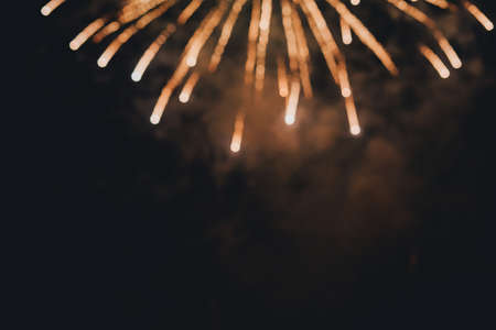 Bright festive background with fireworks. A beautiful gleam of golden salute in the sky. Festive background. Selective focus.の写真素材