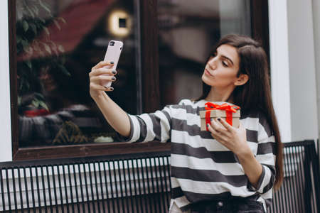 A girl takes a selfie on her smartphone in a light silicone case.の写真素材