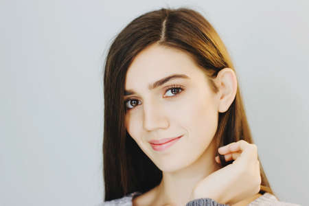 Beautiful smiling brunette girl on grey background.