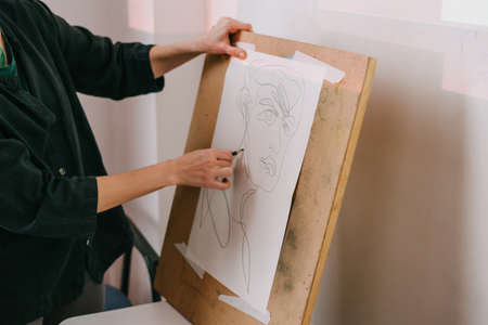 Work out a new technique of drawing portraits. Sketch. Drawing with colored pencils. A master class in portrait painting in an interesting technique. The girl is in the process of drawing.の写真素材