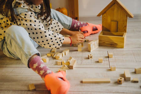 Wooden children's construction kit. Toys made of eco-friendly material. The castle is made of wooden cubes. Children's room. Eco-toys. The girl builds a tower out of a wooden construction kit.の写真素材