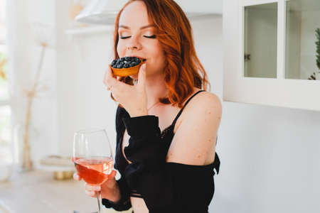 The girl is sitting eating a cake and drinking wine.の写真素材