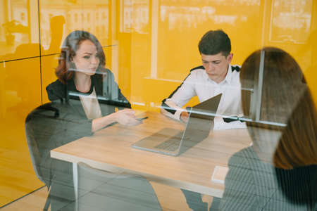 A group of young people is working on a project in a modern office with yellow walls. Double...