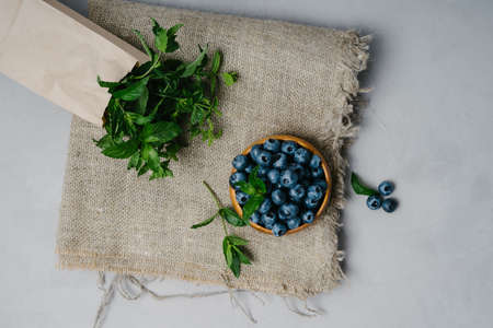 A small wooden bowl with berries and branches of fragrant mint.