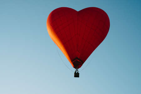 The romance of flying in a balloon in the shape of a red heart.の写真素材