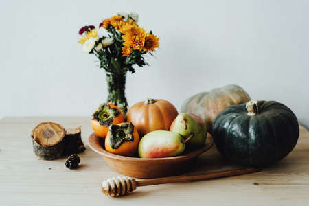 Happy Thanksgiving. A plate of natural material. Reusable utensils. Eco-friendly tableware. Pumpkins, pears and persimmons. Festive composition with an autumn bouquet of flowers, fruits, vegetables.の写真素材