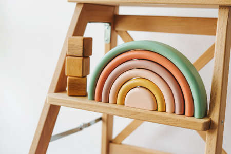 On a wooden shelf there are cubes and a rainbow. Children's room decor. Environmentally friendly toys for children. Wooden rainbow made of natural wood. Zero waste toys.の写真素材