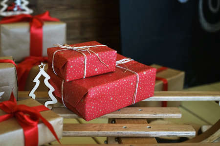Christmas gifts in red and craft packaging. Close-ups of New Year's gifts lie on wooden sleds. Gifts in beautiful craft wrapping paper.の写真素材
