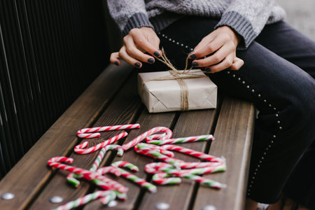 Girl in a grey sweater ties a bow on a gift.