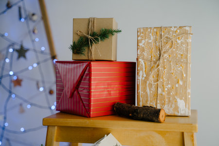 A red box with gold stripes, a kraft box with splashes of paint and a box with a coniferous branch. Blue flashlights in defocus on the background. Colorful gift boxes for the Christmas holidays.の写真素材