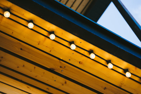 Retro light bulbs on the wooden roof of the coffee shop. Beautiful and eye-catching street decoration of the restaurant. Garland on the wooden ceiling of the terrace.の写真素材