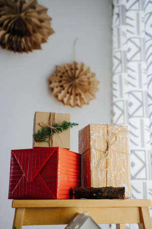 A red box with gold stripes, a kraft box with splashes of paint and a box with a coniferous branch....