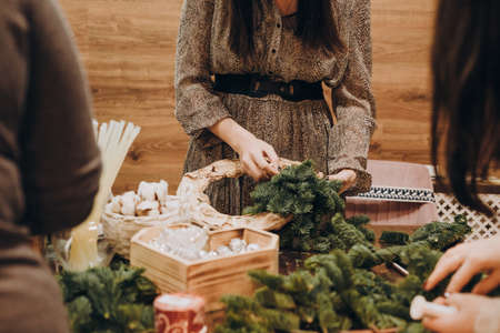 Woman making christmas wreath. Concept of florist's work before christmas holidays. Creating a Christmas wreath of spruce branches and a cardboard frame. Decoration for the house for Christmas.の写真素材