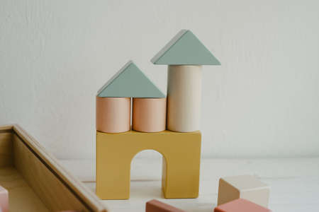 Wooden building blocks - home concept. Toy castle made of bright building blocks on white...