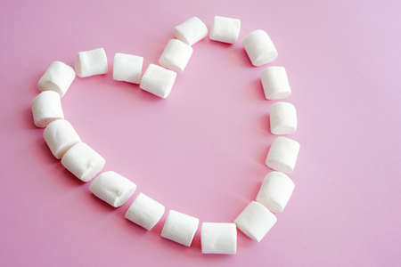 Valentines Day card. Marshmallow heart is laid out on a pink background.の写真素材