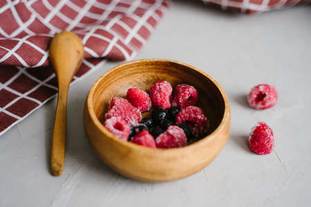 Juicy frozen berries in a wooden plate.