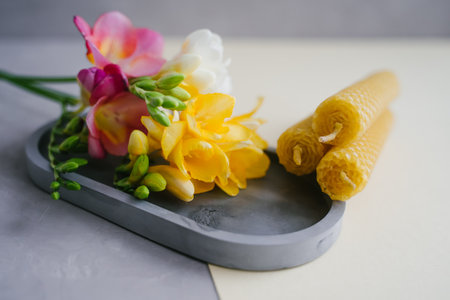 A candle lit on a gray tray. Bright freesia flowers.の写真素材