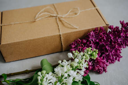 Gift and a branch of lilac flowers. Delivery of goods to the door. The package.の写真素材