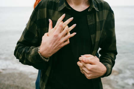 The embrace of a couple in love on the seashore. The girl hugs the guy from behind. A couple in love holding hands.の写真素材