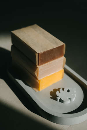 Soap or shampoo made from natural materials. Gray oval handmade plaster tray. Solar hard light from the window. Homemade soap with herbs. Fragrant Natural Soap. vertical photo.の写真素材