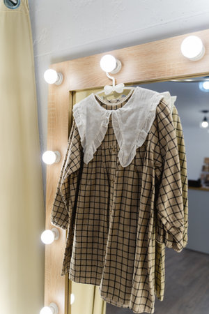 Dress with a white collar in a fitting room with a large mirror. Childrens clothing store.の写真素材