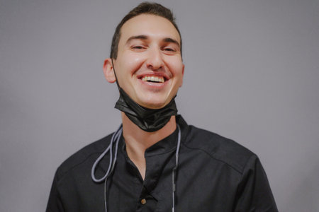 Smiling dentist in black uniform and mask. Close-up portrait of a professional man.の写真素材